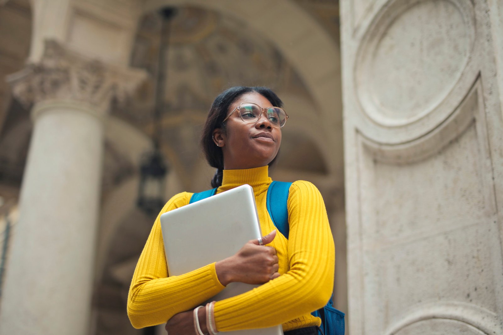 portrait of young woman with laptop in hands outside a school